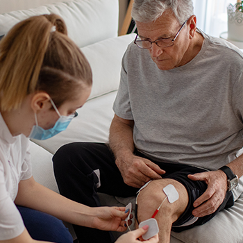 Female nurse assisting an elderly man.